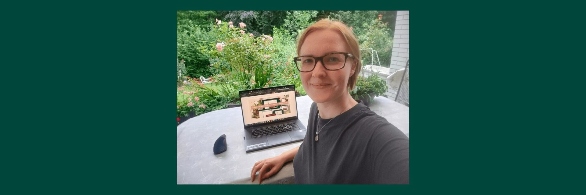 Isabell Fabo arbeitet am Tisch im Garten mit Blick in den Wald